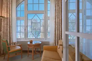 Suite Wohnzimmer mit Couch und Tisch, Fenster im Hintergrund.