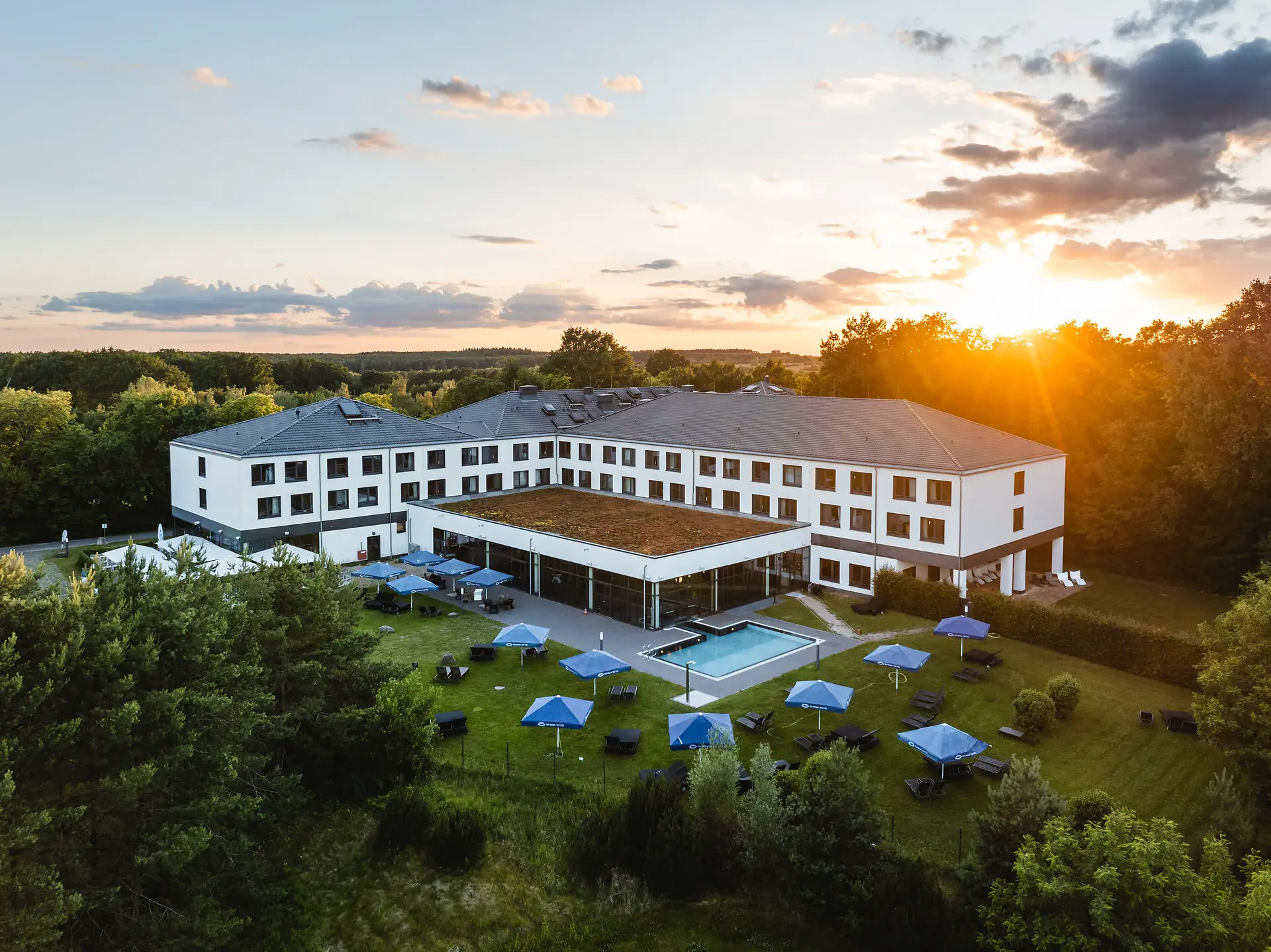 aja Bad Saarow Ein Gebäude mit einem Pool und Sonnenschirmen.