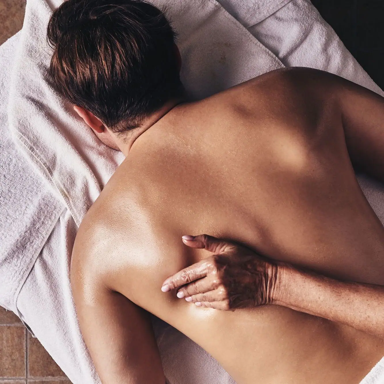 Massage Eine Person liegt mit dem Rücken auf einem Handtuch.