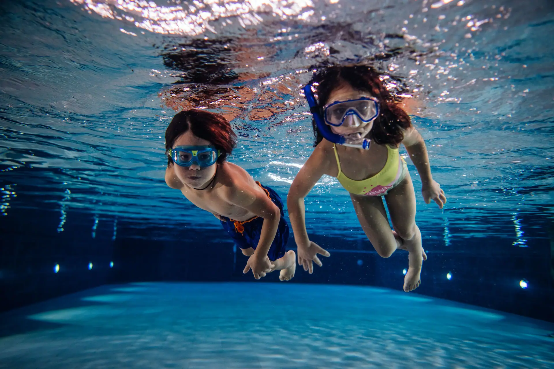 Kinder tauchen im Pool Mehrere Personen schwimmen unter Wasser im Schwimmbecken.