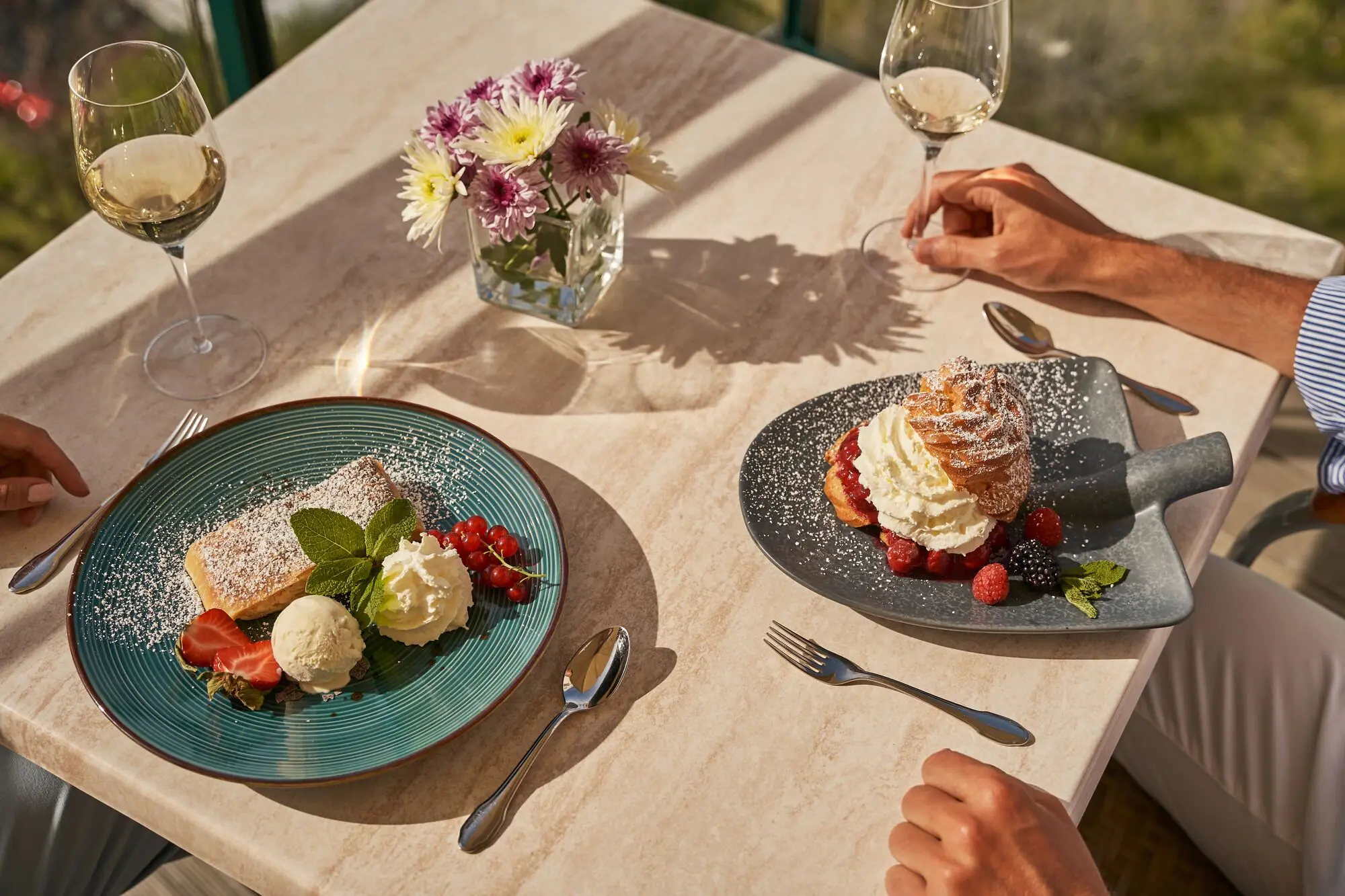 Gebäck Essen mit Wein auf der Terrasse. Ein Mann und eine Frau sitzen an einem Tisch im Freien mit Getränken und Essen.