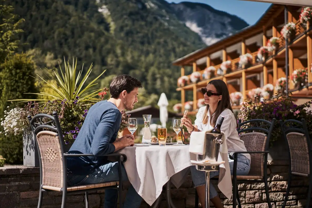 Außenterrasse Ein Mann und eine Frau sitzen an einem Tisch mit Getränken.
