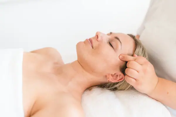 Anwendung im aja Grömitz Frau liegt auf einem Massagetisch.