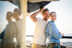 Warnemünde Paar Ein Mann und eine Frau stehen lächelnd auf einem Boot.