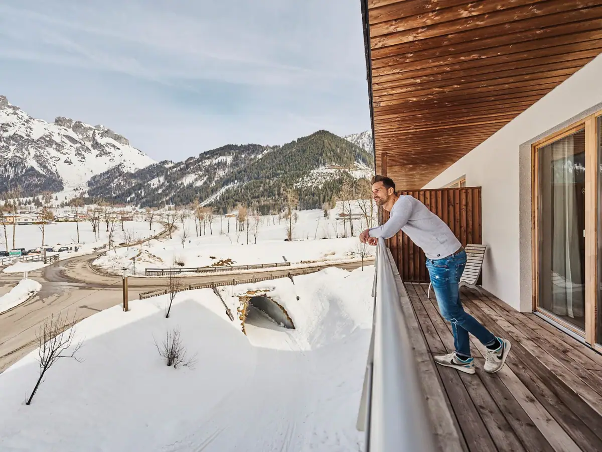 Balkon Werfenweng Ein Mann steht auf einem verschneiten Balkon.
