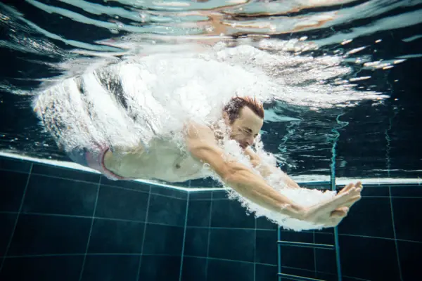Schwimmen im Pool Ein Mann schwimmt unter Wasser mit Blasen.