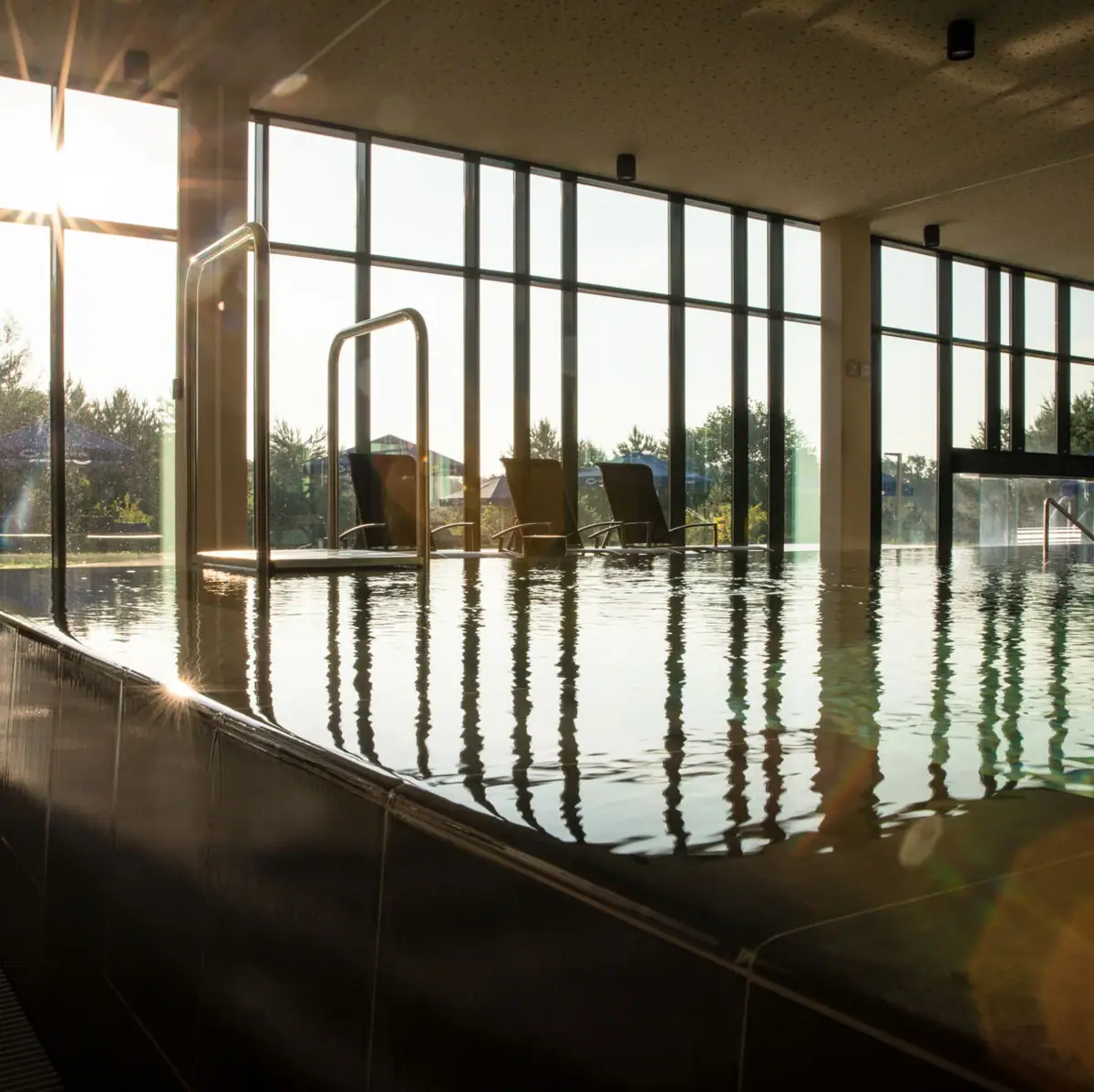 Kontakt & Öffnungszeiten Ein Pool mit großem Fenster und Wasserreflexionen.