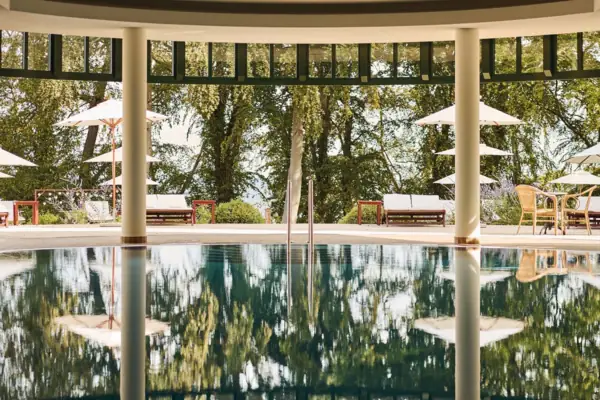 Innenpool Ein Pool mit Sonnenschirmen und Stühlen im Hintergrund.