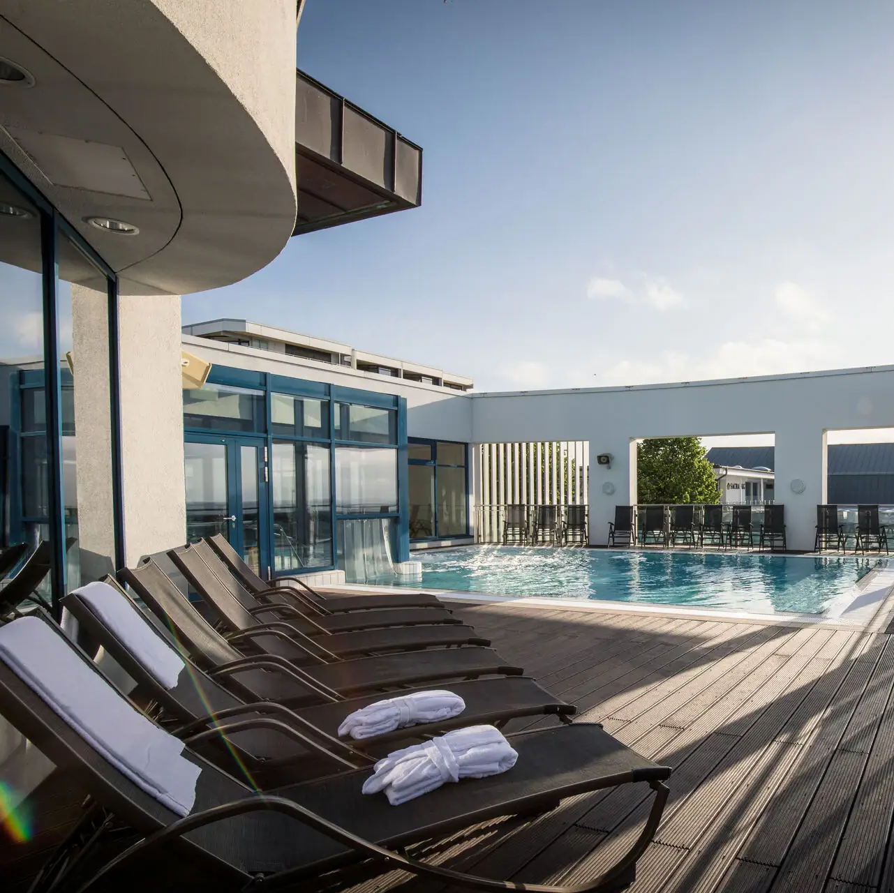 Außenpool Grömitzer Welle Ein Pool mit Liegestühlen und einem Deck im Freien.