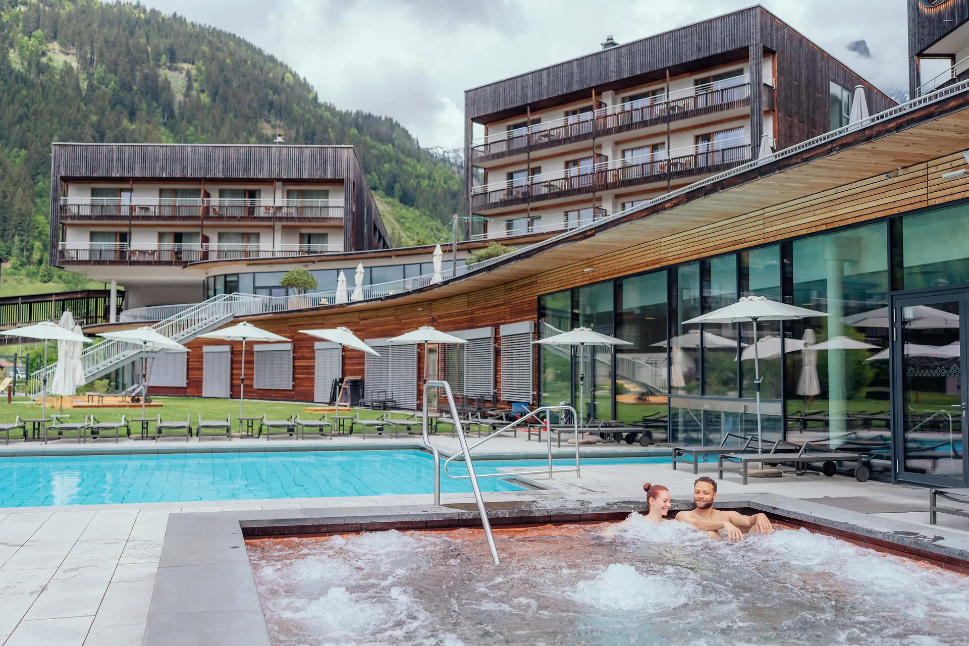 aja Bergresort Werfenweng Ein Paar in einem Whirlpool im Freien.