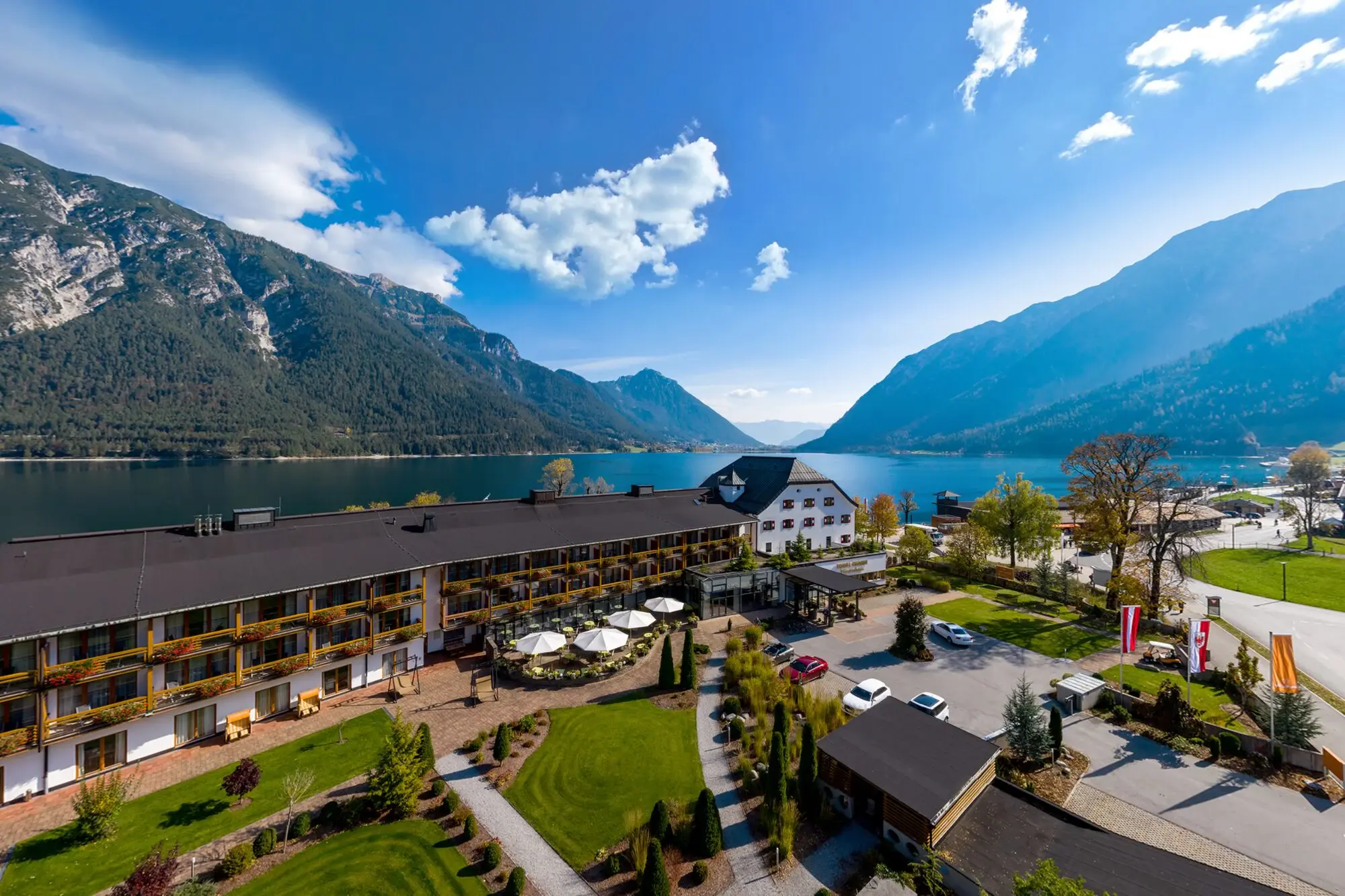 Das aja Fürstenhaus am Achensee direkt am Achensee, umgeben von Bäumen und Bergen.