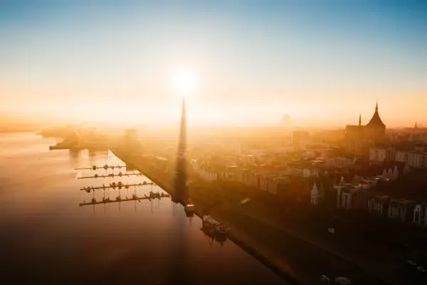 Eine Stadt mit einem Gewässer und einem hohen Turm im Morgengrauen.