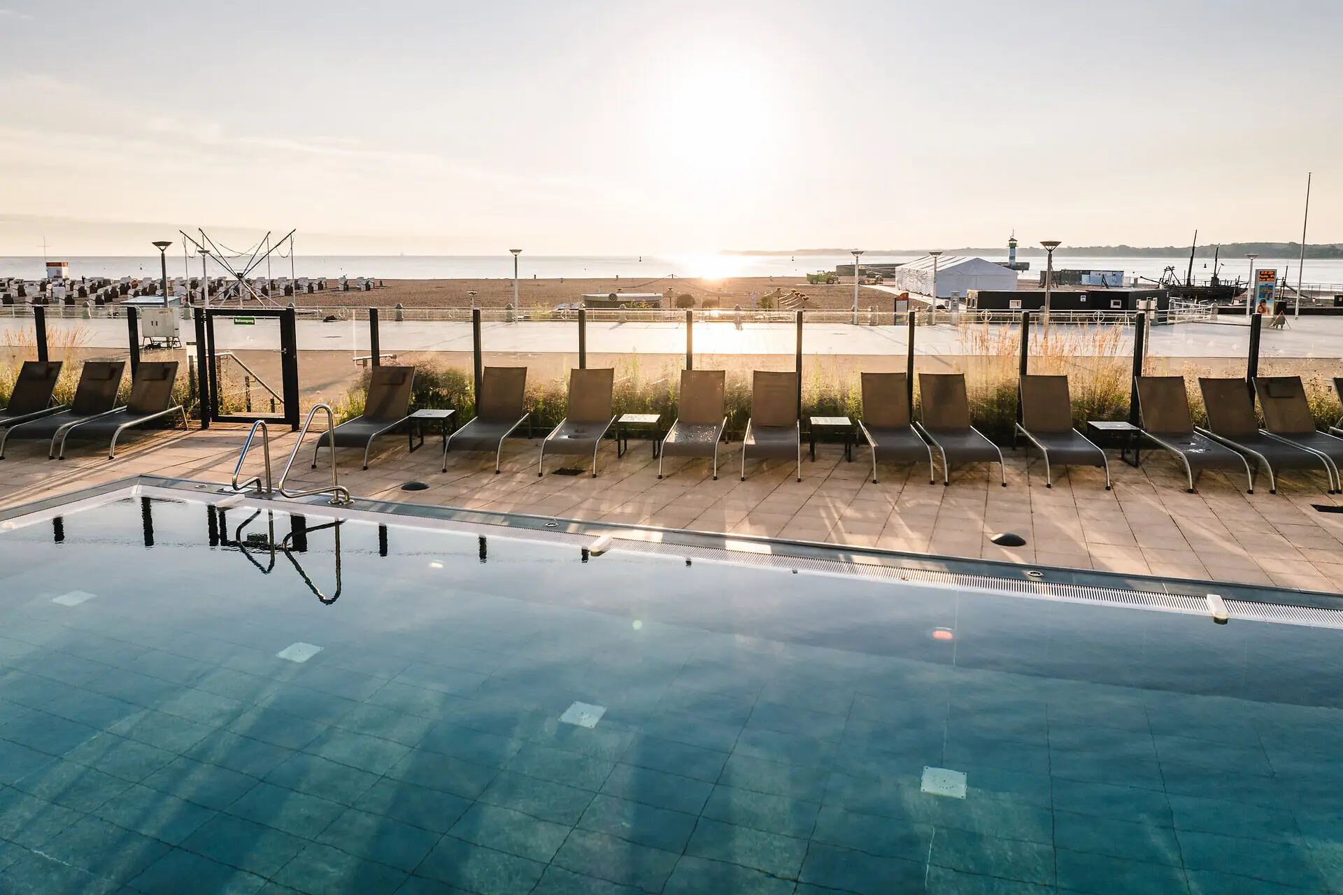 Ein Pool mit Stühlen und einem Strand im Hintergrund.