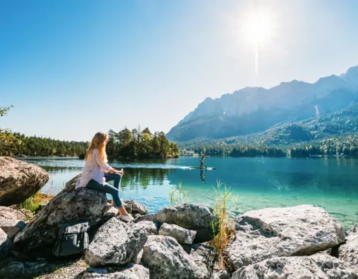 Eibsee Eine Frau sitzt auf einem Felsen am See.