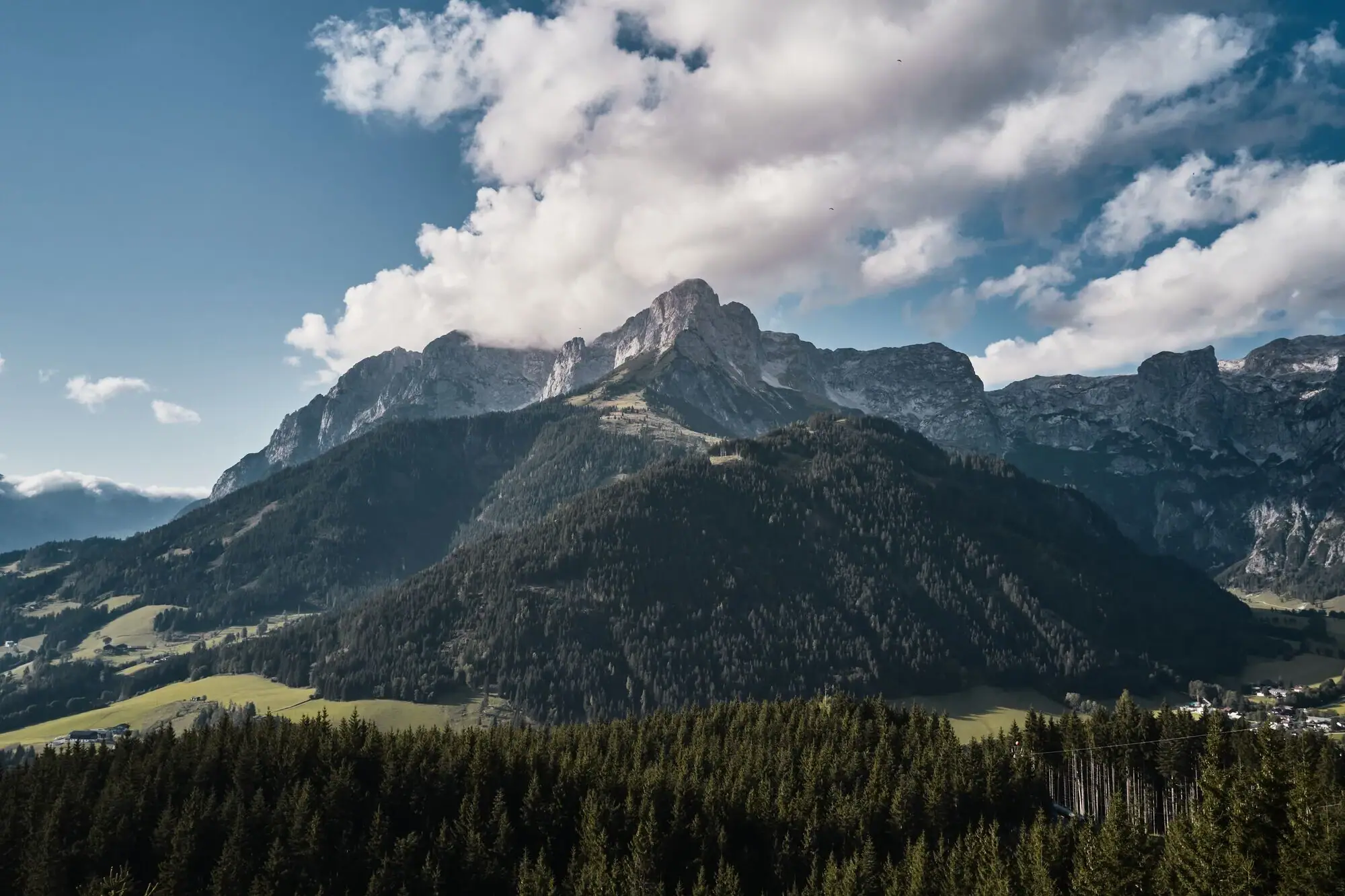 Berglandschaft mit Bäumen und Wolken.