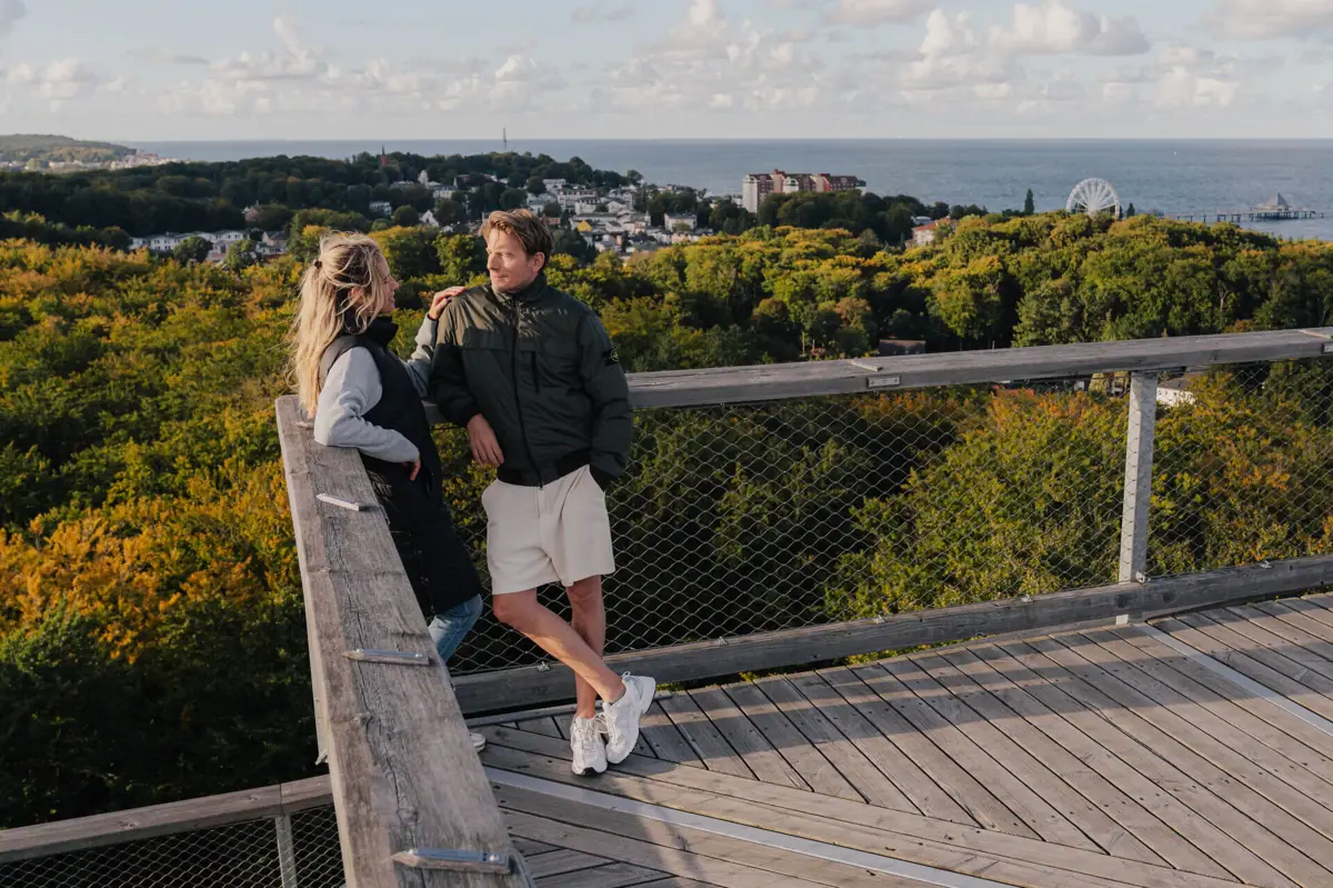 Aussicht vom Baumwipfelpfad Ein Mann und eine Frau stehen auf einem Holzdeck mit Blick auf einen Wald.
