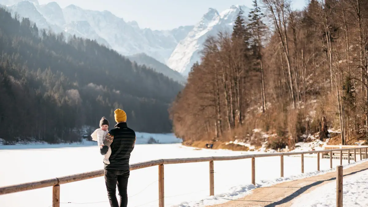 Riessersee in Winter Ein Mann hält ein Baby auf einer verschneiten Straße.
