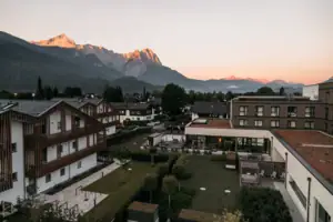 Ausblick Eine Gruppe von Gebäuden mit Bäumen und Bergen im Hintergrund.