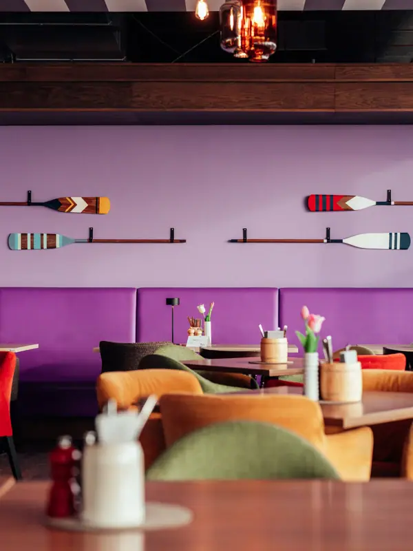 Restaurant Ein Raum mit Tischen und Stühlen und einer lila Wand mit Rudern.