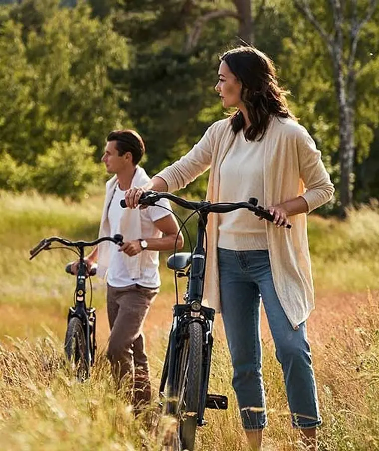 aja Bansin Fahrrad Ein Mann und eine Frau mit Fahrrädern stehen auf einer Wiese.