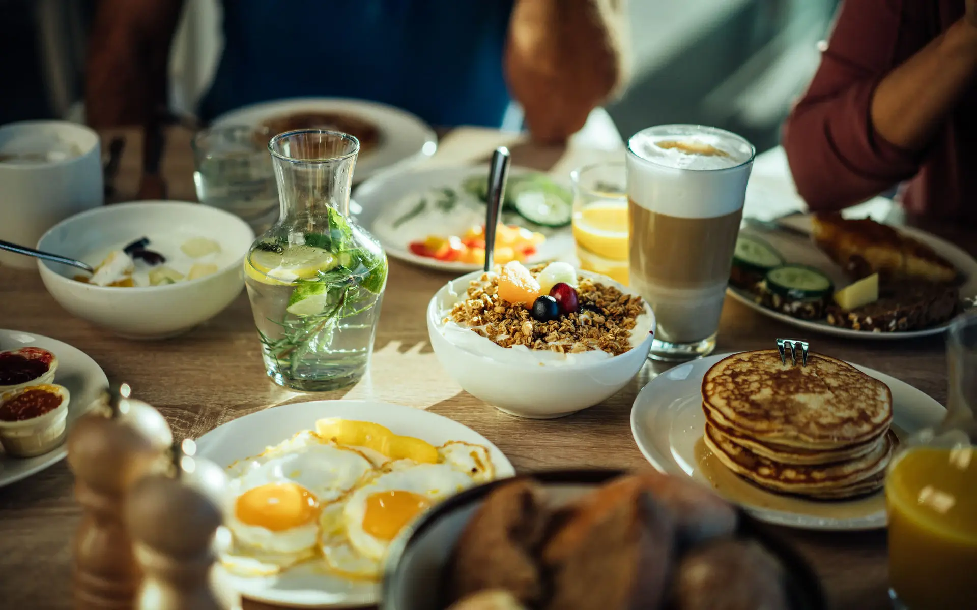 Ein appetitlich gedeckter Frühstückstisch mit Müsli, Pancakes, Eierspeisen und vielem mehr.