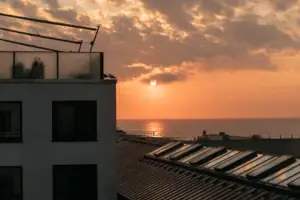 aja Grömitz Ein Gebäude mit Dach vor einem Sonnenuntergang.