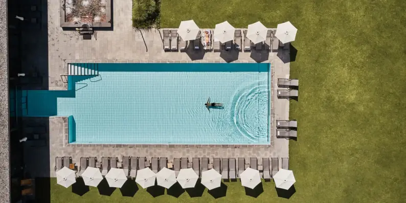 Vogelperspektive von einem Pool umgeben von Sonnenschirmen und Grasfläche. Vogelperspektive von einem Pool umgeben von Sonnenschirmen und Grasfläche.
