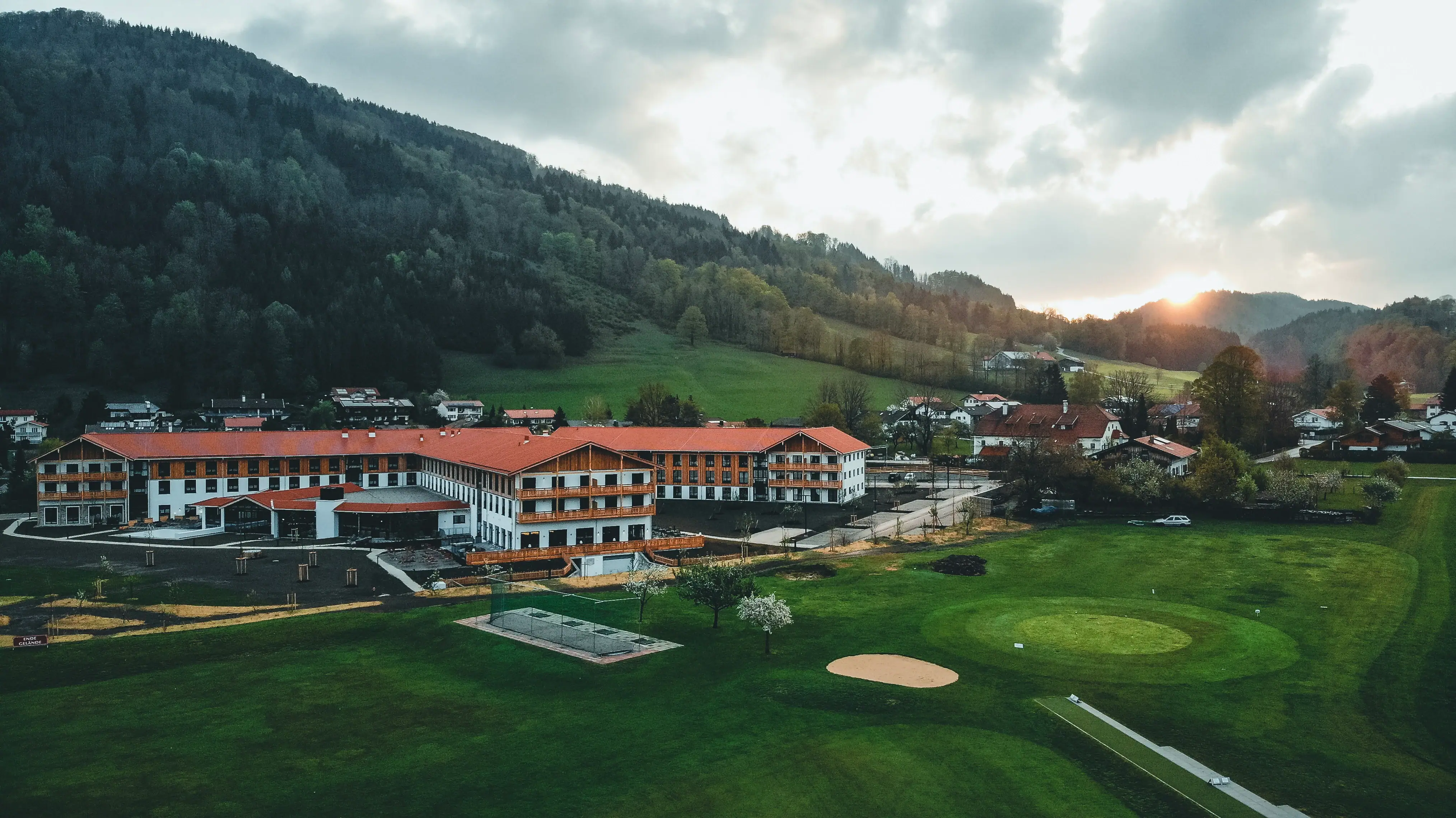 aja Ruhpolding Großes Gebäude mit Golfplatz und Bäumen im Hintergrund.