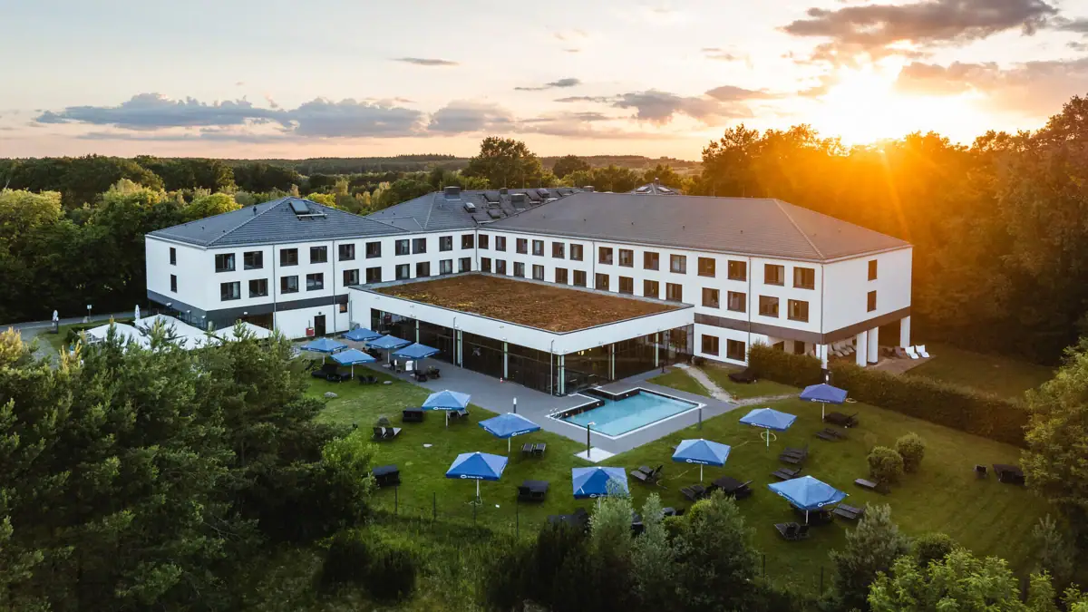 aja Bad Saarow Ein Gebäude mit einem Pool und Sonnenschirmen in der Mitte.