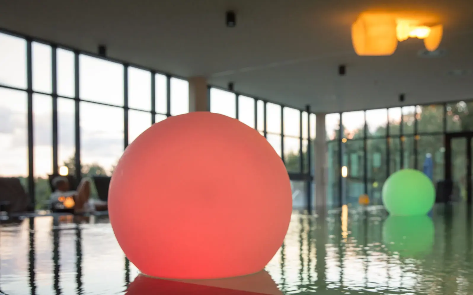 Kinderpool aja Bad saarow Ein Poolbereich mit großen runden Kugeln in rot und grün darin. Die großen Fenster im Hintergund füllen den Bereich mit Tageslicht.