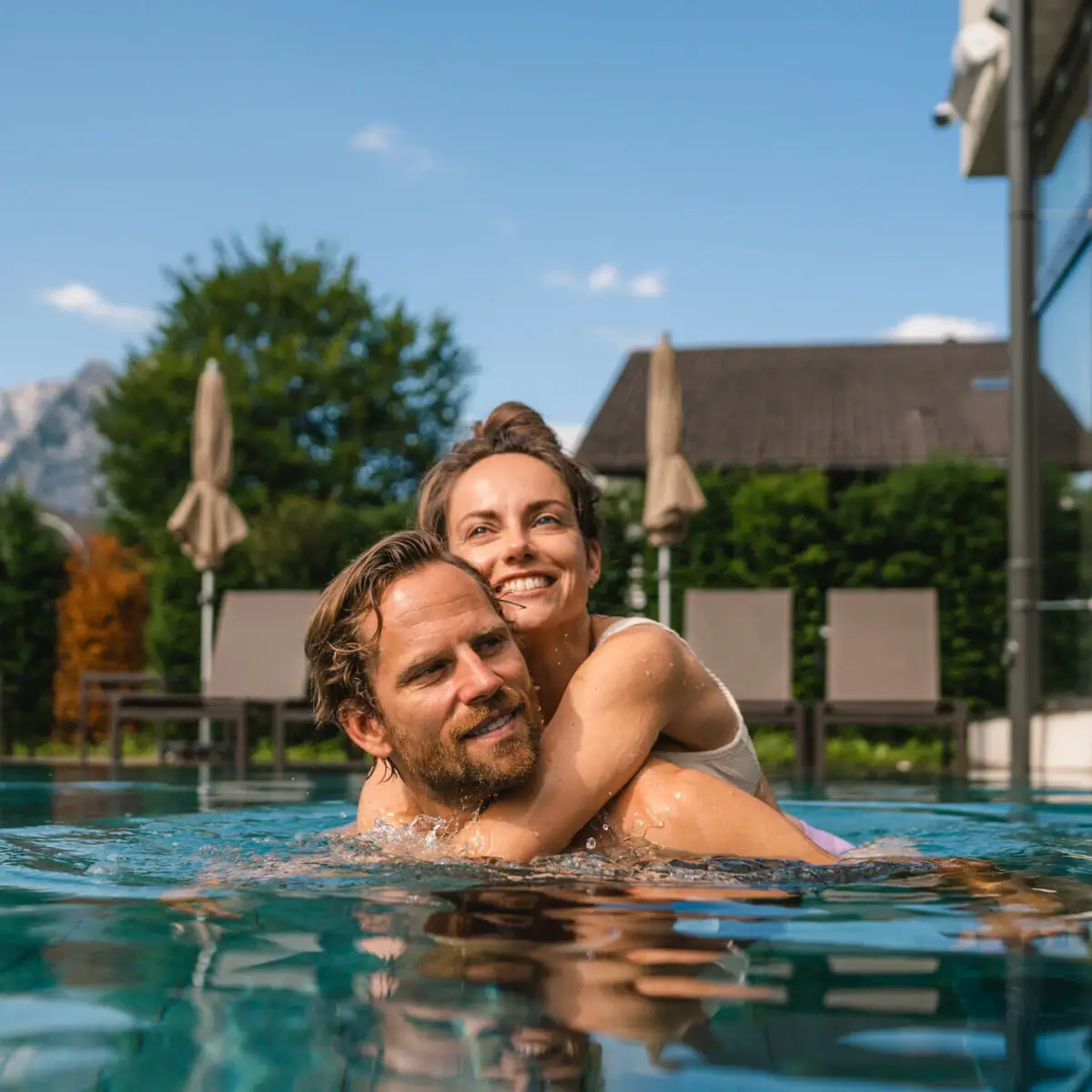 Außenpool aja Garmisch Partenkirchen Ein Mann und eine Frau im Pool, beide lächelnd.