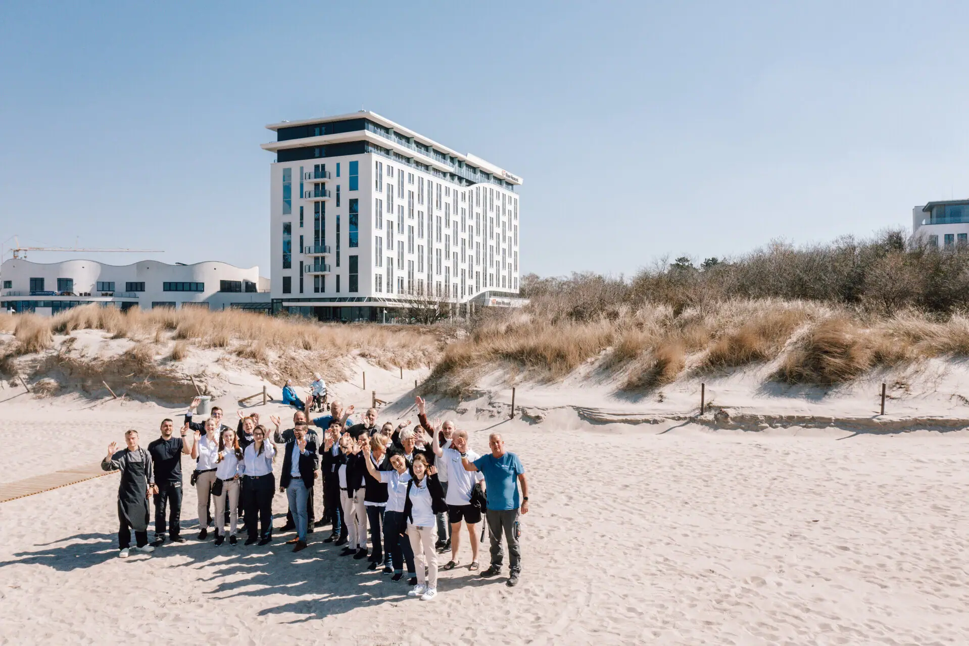 Team aus dem aja Warnemünde Eine Gruppe aus Menschen vom Team des Hotels posiert für ein Foto vor dem aja Warnemünde Gebäude.