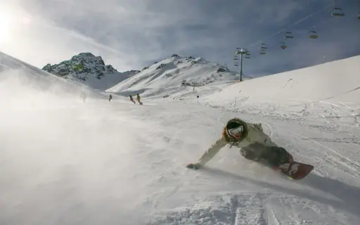 Person auf einem Snowboard fährt eine verschneite Piste hinunter. Person auf einem Snowboard fährt eine verschneite Piste hinunter.