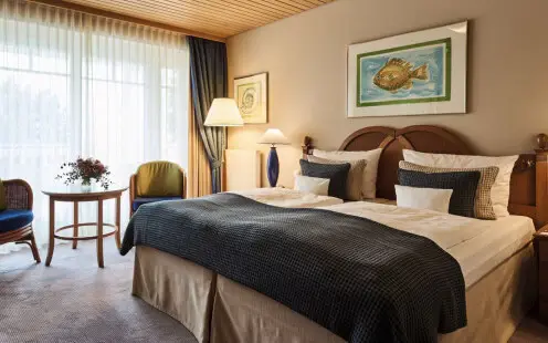 Doppelzimmer Komfort aja Bansin Ein Schlafzimmer mit einem gemachten Bett, Nachttisch und Tisch, ausgestattet mit Kissen, Bettwäsche und einem Duvet.