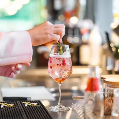 Bar im aja Bad Saarow Eine Person legt ein Blatt auf ein Getränk in einem Weinglas.