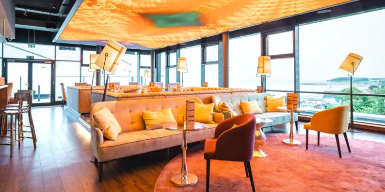Ein warm beleuchteter Barbereich mit großen Sofas und gemütlichen Sesseln. Ein warm beleuchteter Barbereich mit großen Sofas und gemütlichen Sesseln.