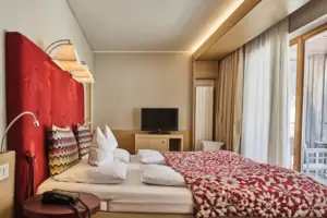 Schlafzimmer Bett mit einer rot-weißen Decke und einem Fernseher im Hintergrund.