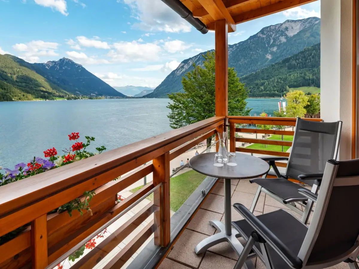 Balkon Ein Balkon mit Tisch und Stühlen mit Blick auf einen See.
