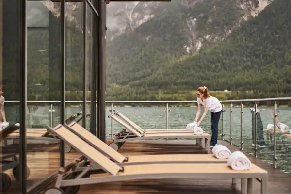 Liegestühle am See Eine Frau reinigt ein Deck mit Handtüchern.