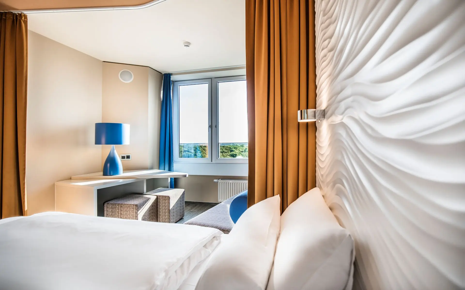 Ein Zimmer mit einem Bett, einem Schreibtisch, sowie einem Fenster
