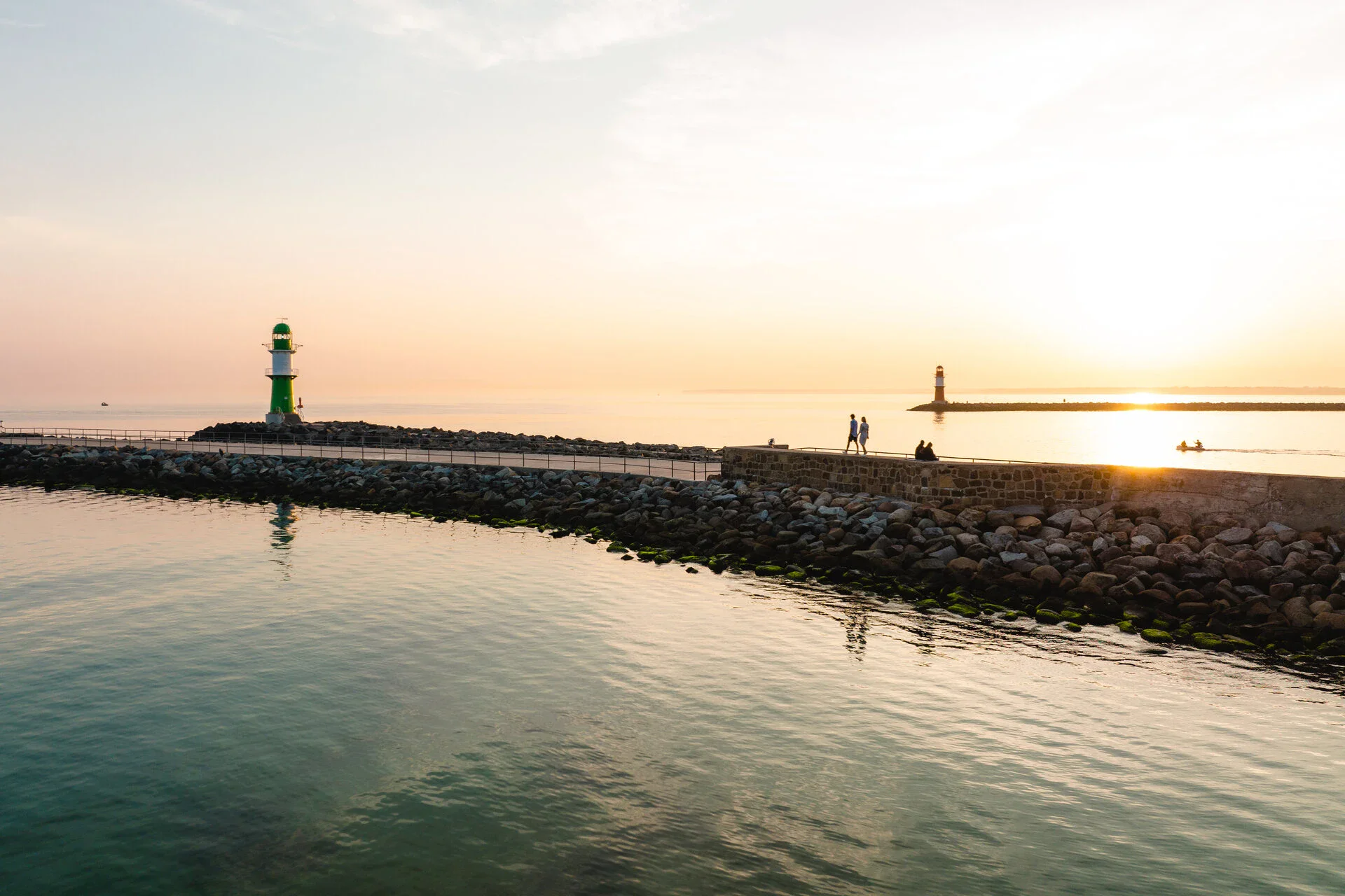 Ein Steg mit Leuchtturm am Ende führt aufs Wasser hinaus.