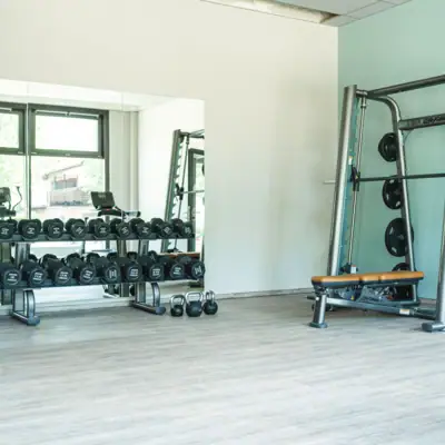 Kraftbereich Ein Fitnessstudio mit Gewichten und einem Regal voller Geräte.