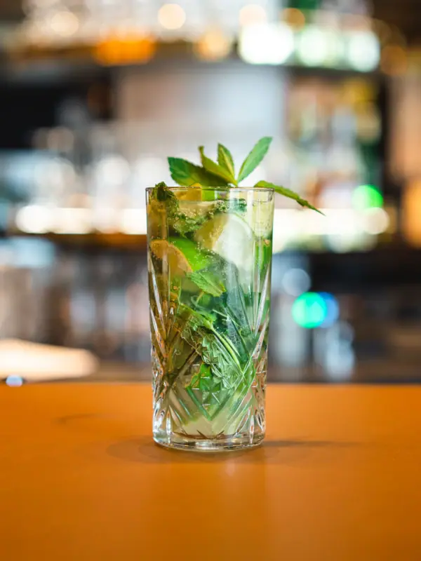 Mojito Drink Ein Glas mit einem Getränk, garniert mit Limetten und Minzblättern in der aja Bar Garmisch-Partenkirchen..