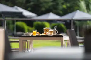 Frühstück Terrasse Ein Frühstückstisch mit Essen darauf auf einer Terrasse im Grünen.