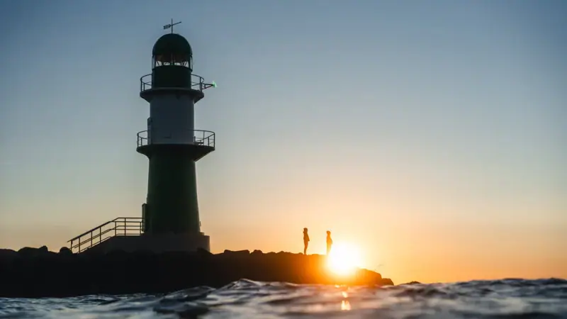 Ein Leuchtturm im Wasser bei Sonnenuntergang.
