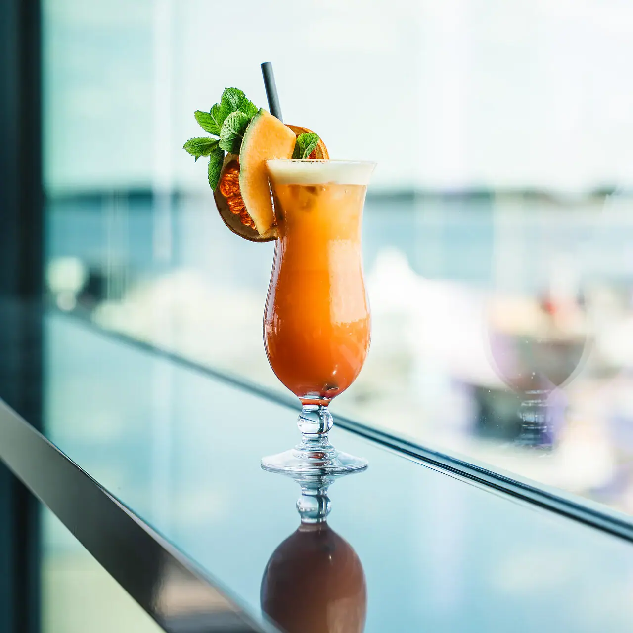 Ein Glas mit einem Cocktail und Garnitur auf einem Tisch.