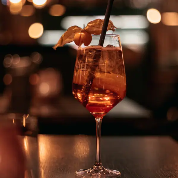 Aperol Spritz Ein Glas mit einem Getränk, Strohhalm und Obst.