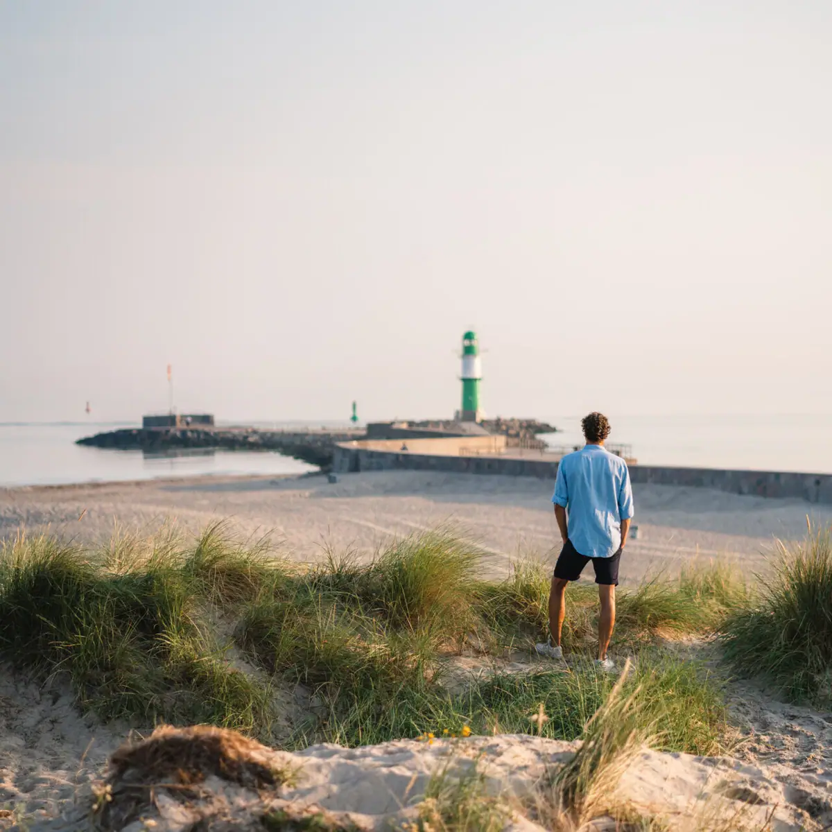 Erlebnisse im aja Warnemünde Ein Mann steht am Strand und blickt auf einen Leuchtturm.