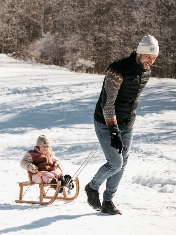 Schlittenfahren in den Bergen Ein Mann und ein Kind auf einem Schlitten im Schnee.
