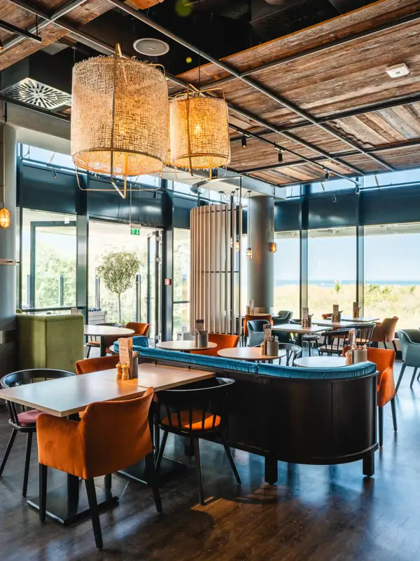 Restaurant und Bar im aja Warnemünde Ein Restaurant mit Tischen und Stühlen. Modern und maritim eingerichtet.